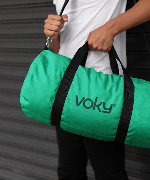 N&auml;rbild p&aring; en man som b&auml;r en gr&ouml;n duffelv&auml;ska med Voky-m&auml;rke